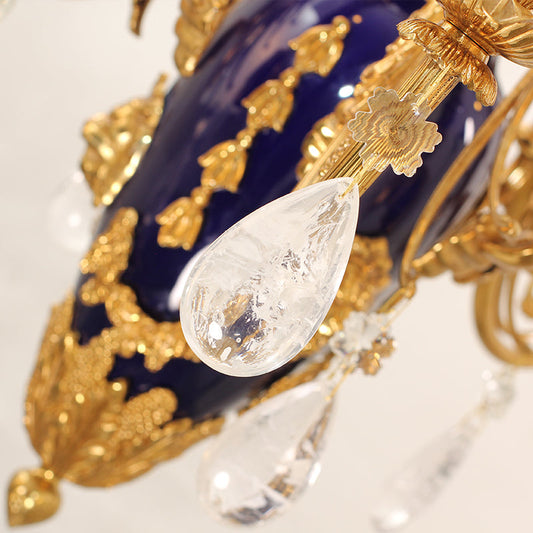 Close‑up of ornate brass scrollwork and crystal teardrop on ceramic chandelier