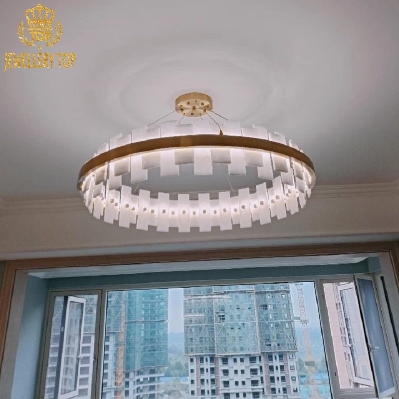 Geometric chevron patterns on polished brass column of stone chandelier