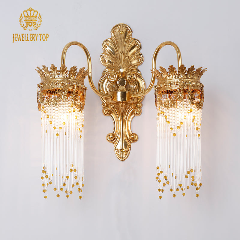 Frontal view of the Aurelia Cascade gold wall sconce showing its ornate backplate and glass rods