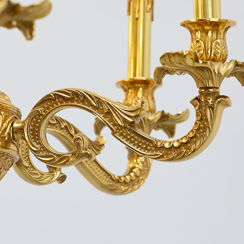 Curving arms of a brass chandelier supporting candle-inspired light holders.