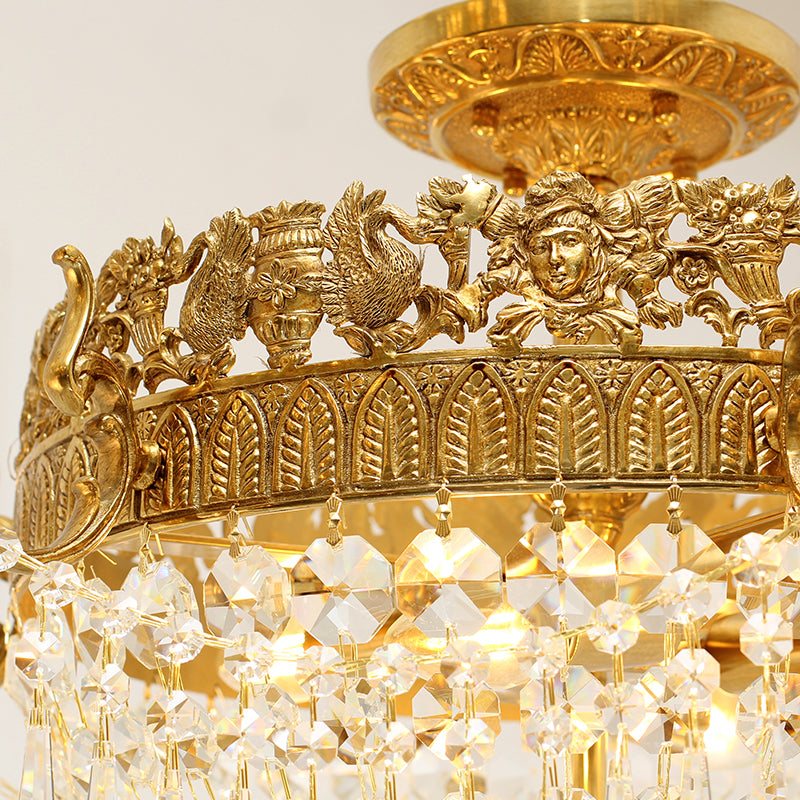 Detailed brass artwork showing mythical figures on antique crystal ceiling lamp.