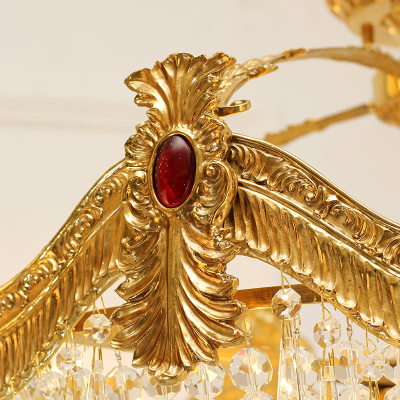 Close-up of intricate brass garland decoration accented by ruby-red gemstone.
