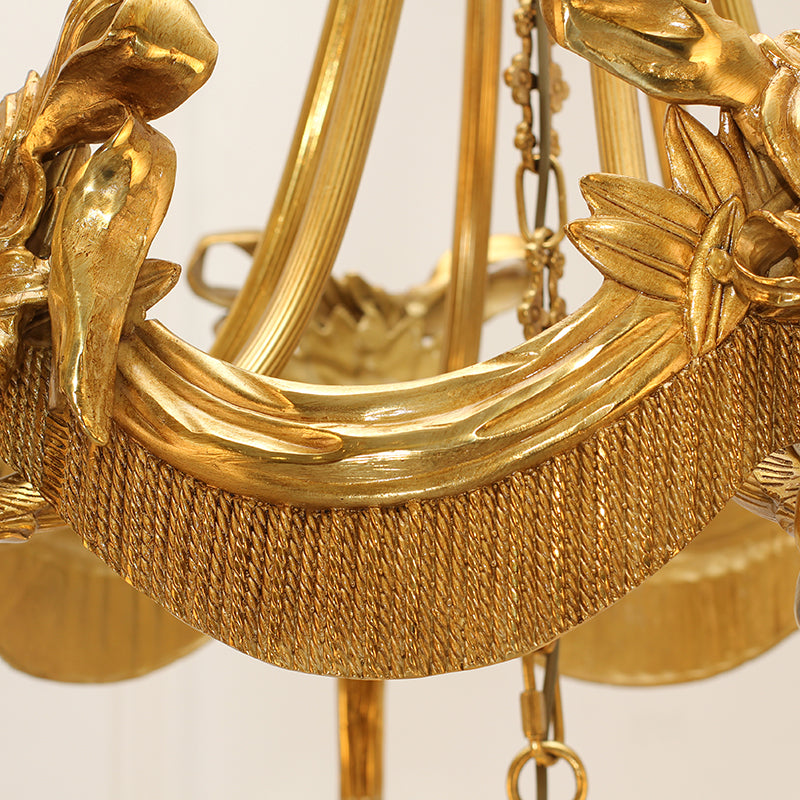 Detailed view of sculpted drapery elements adorning a brass chandelier.