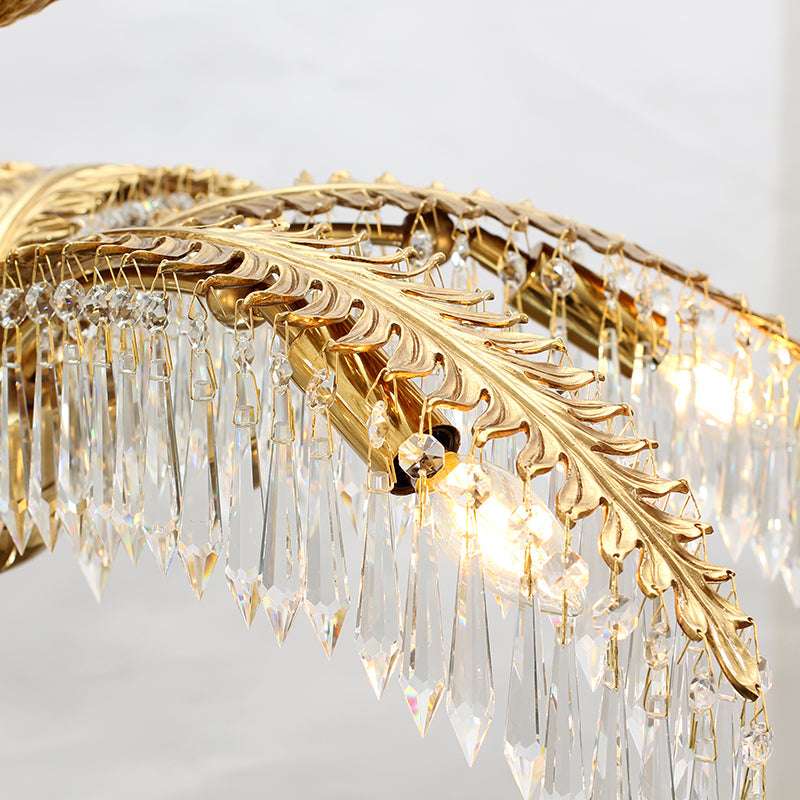 Detailed view of palm leaf chandelier featuring brass accents and shimmering crystals.