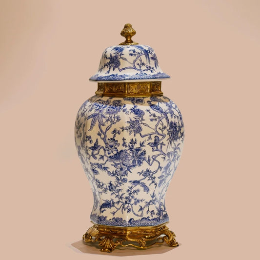 Close-up of ceramic jar's ornate brass tripod base with acanthus scrollwork and white-blue floral body.