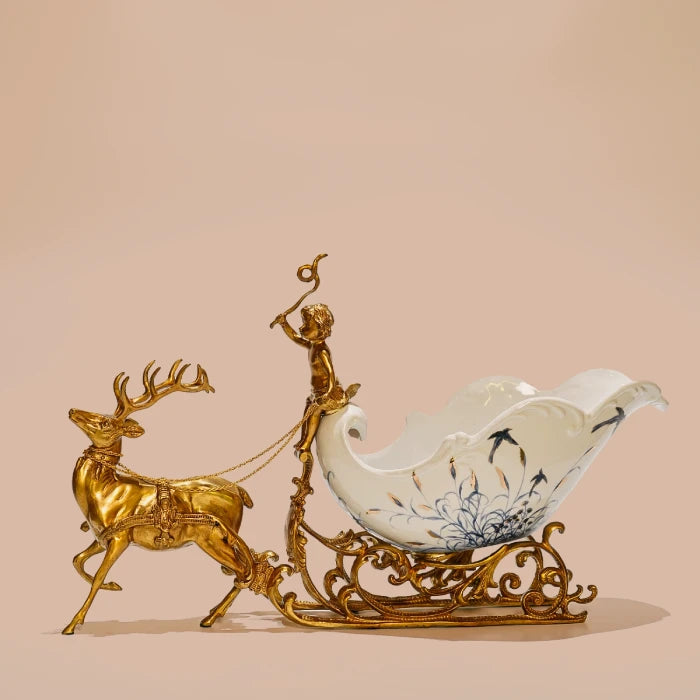 Decorative ornament featuring brass stag pulling ceramic chariot with blue floral motifs