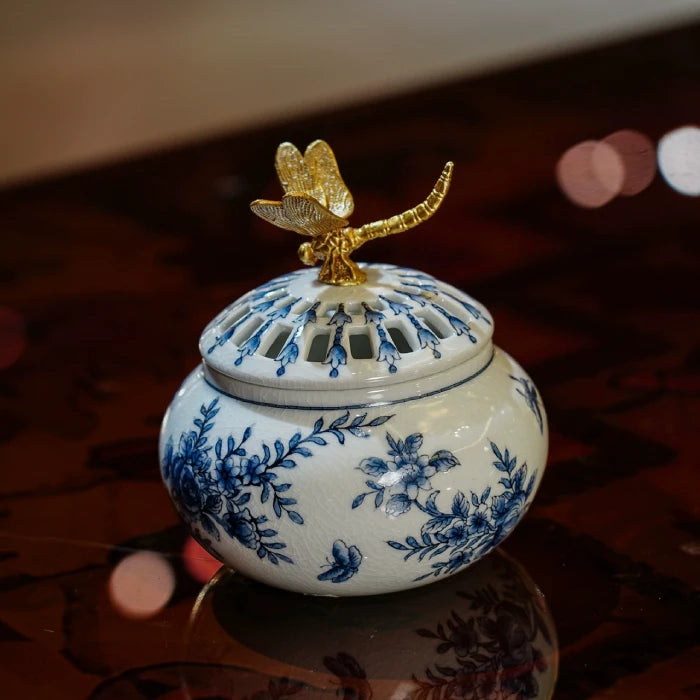Close-up of blue floral and butterfly patterns on white ceramic aroma stove surface