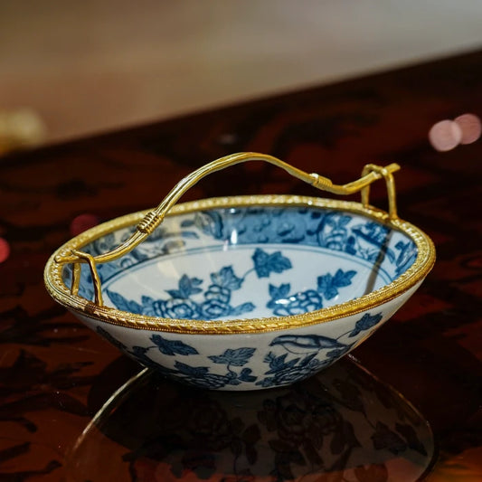 Close-up of blue bird and floral patterns on white ceramic candy dish with gold rope edge