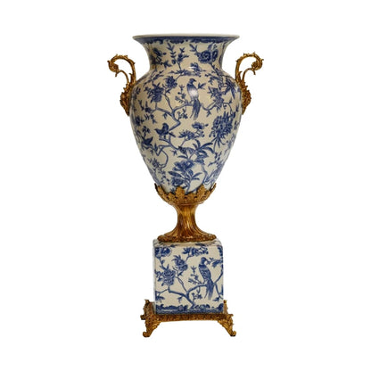 Front perspective of a blue and white porcelain vase with bird and floral motifs, and brass side handles.