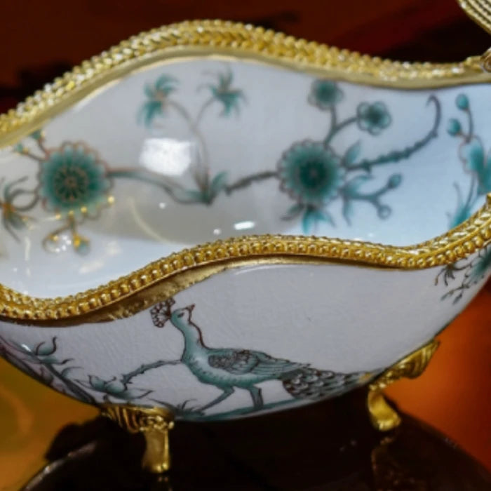 Detailed shot of brass tendril designs and moth motifs on ceramic candy bowl
