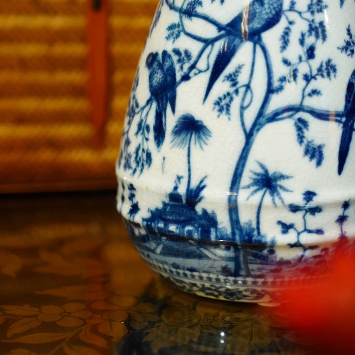 Detailed shot of the ceramic bird perched on brass handle of blue white vase