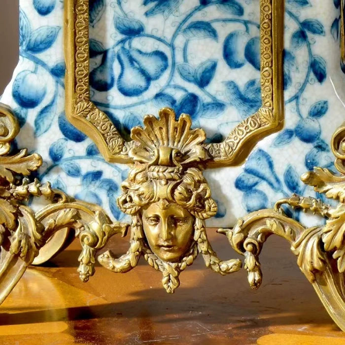 Close-up of the clock’s face with Roman numerals, elegant hands, and intricate brass bezel against blue-white ceramic.