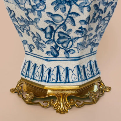 Close-up of a ceramic jar's octagonal brass rim with key pattern and blue fruit motifs.