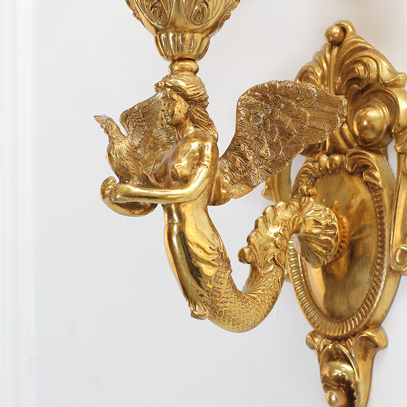 Detailed shot of the mermaid-like sculpture anchoring the sconce’s center