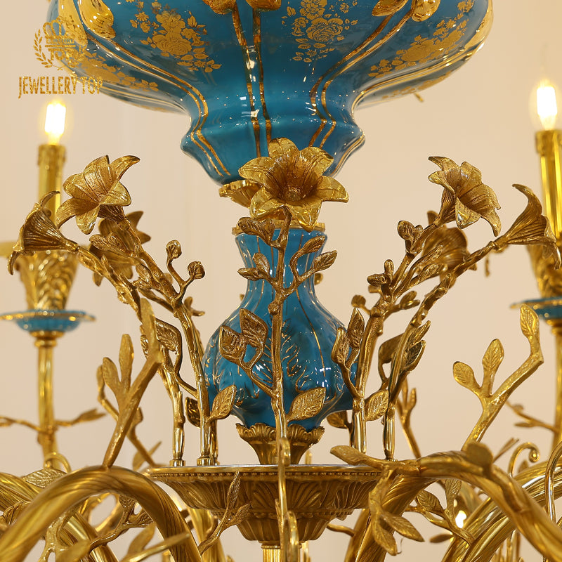 Close-up of golden floral motifs on the ceramic centerpiece of a vintage chandelier.