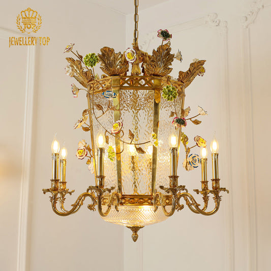 Ornate antique brass chandelier with floral accents and softly glowing glass shades.