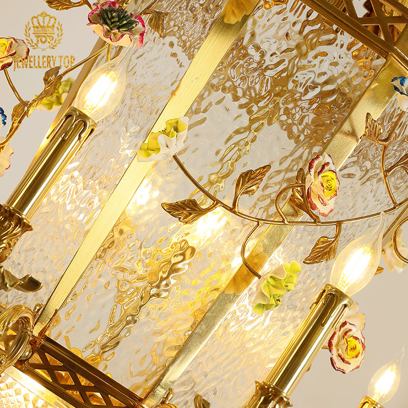 Central column of the antique brass chandelier featuring detailed floral scrollwork.
