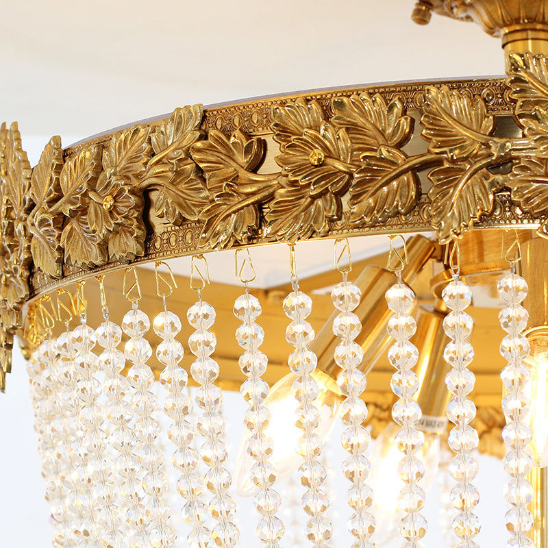 Close-up of floral motifs and crystal strands on a gold ceiling light.