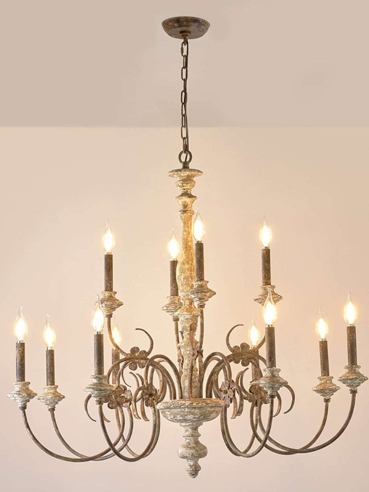 French country chandelier with scrolled iron arms and Edison bulbs in a rustic dining room